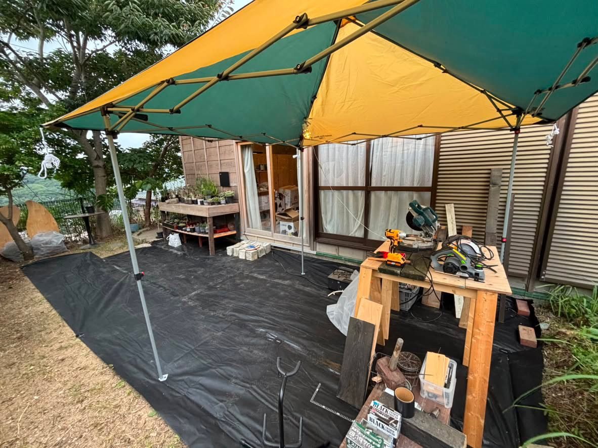 Area di lavoro all'aperto durante l'allestimento del negozio, con gazebo e attrezzi