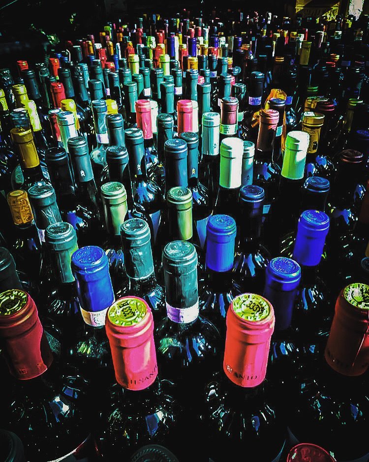 Bottiglie di vino viste dall'alto, con le capsule colorate